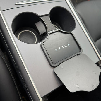 Car cup holder with Tesla logo and phone holder in a Tesla vehicle.